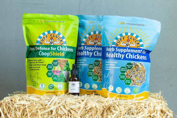 Flock Favorites Bundle with 2 buff clucks herb supplement, 1 coopshield, and 1 aquaboost on a hay bale